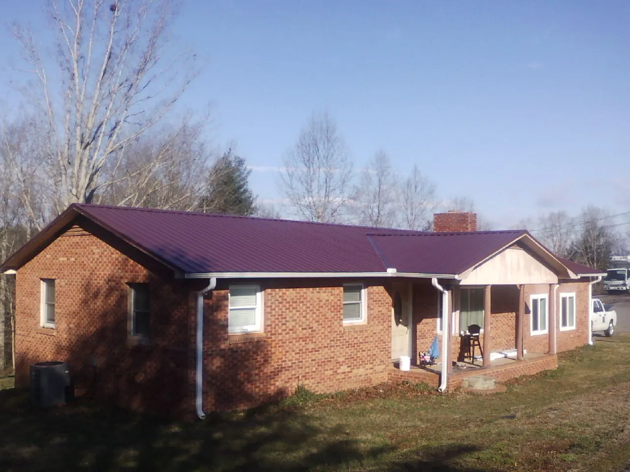 Burgundy metal roof on a brick ranch home with a new addition in Lake Wilson