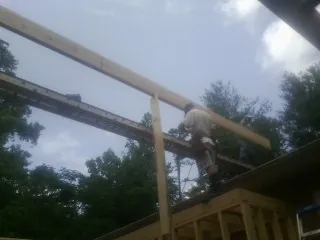 Carpenter setting a ridge beam over a new addition frame — Ice Dam Removal by Roofing Brothers in Lake Wilson