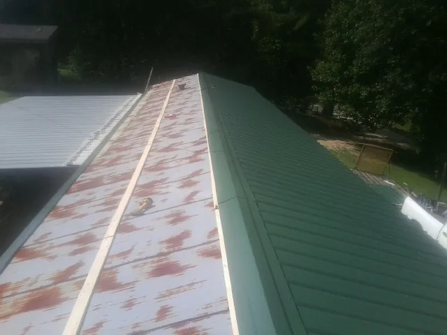 Old rusted panels beside newly installed green metal roofing — Wind Damage Roof Repair by Roofing Brothers in Lake Wilson