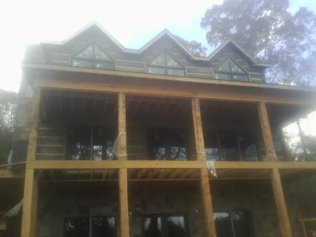 Dormers and porch framing on a large log home under construction — Roof Coating work by our crew in Lake Wilson
