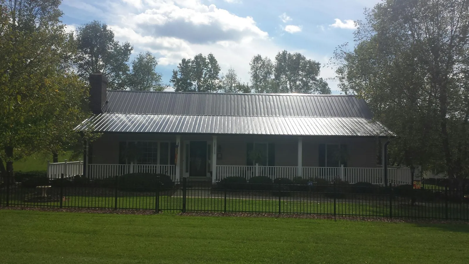 Gray metal roof on a brick ranch with a full width front porch — Gutter Guard Installation work by our crew in Lake Wilson