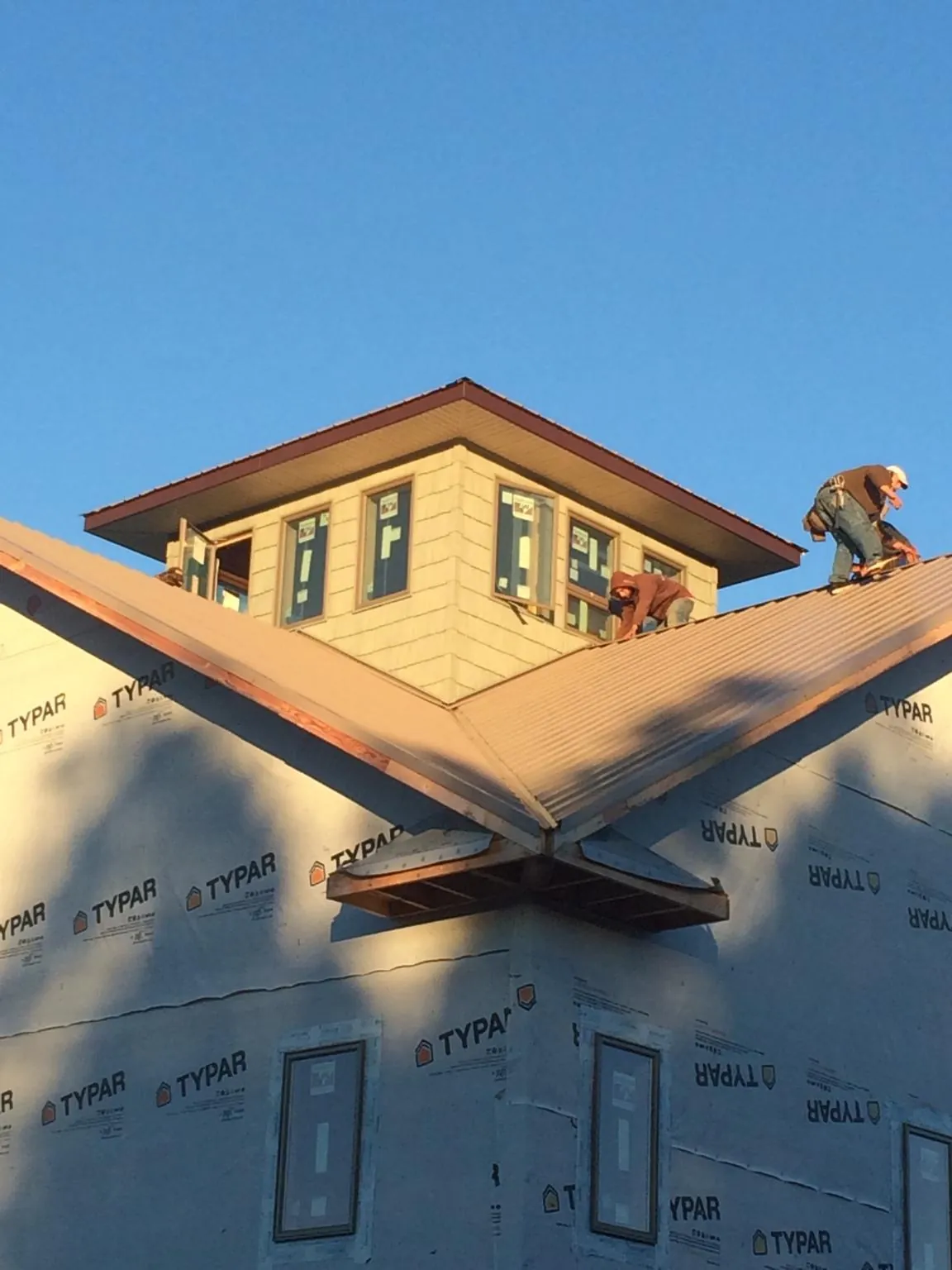 Roofers working around a rooftop cupola on a new metal roof at sunset — Roof Waterproofing in Lake Wilson by Roofing Brothers